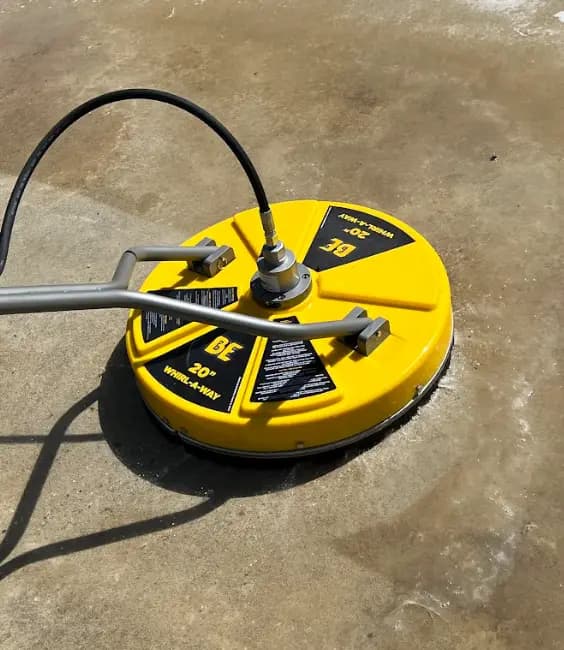 Yellow 20-inch BE Whirl-A-Way surface cleaner on stained concrete, leaving a cleaner lighter path behind it.